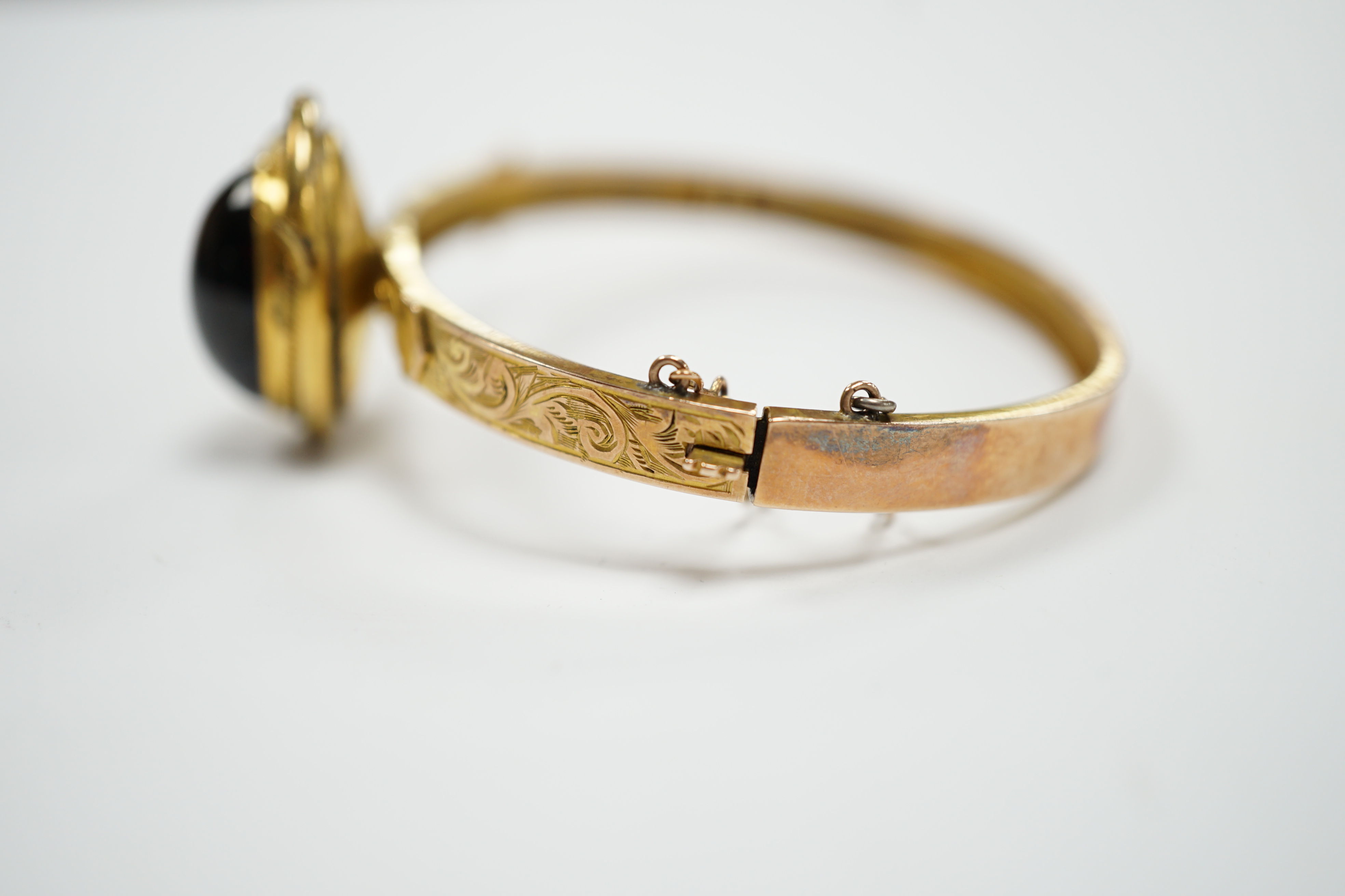 A late Victorian 9ct gold and single stone cabochon red paste set hinged bangle, gross weight 14.5 grams, (adapted?).